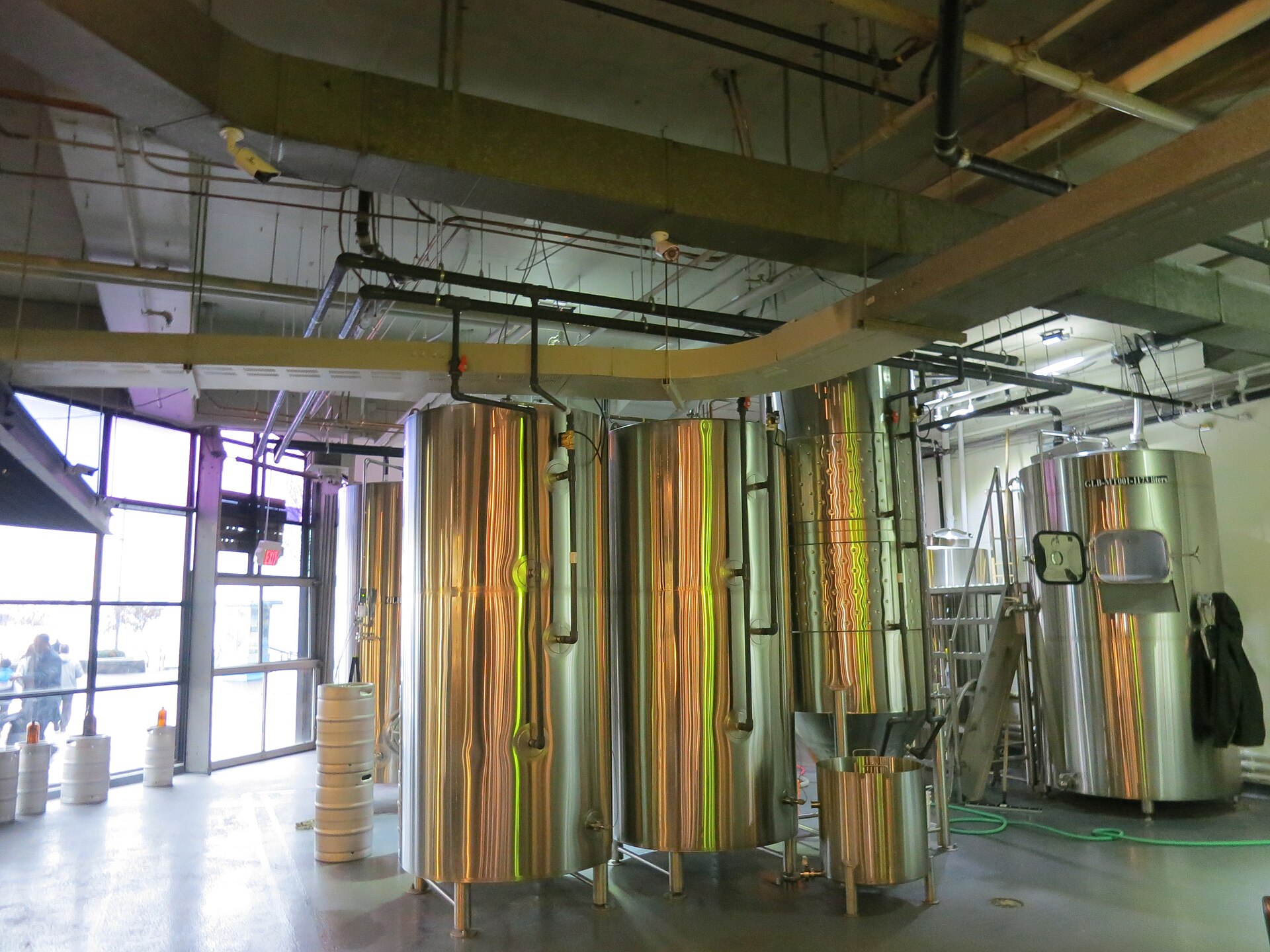 Rows of large stainless steel fermentation tanks lined up on the floor of a craft brewery.