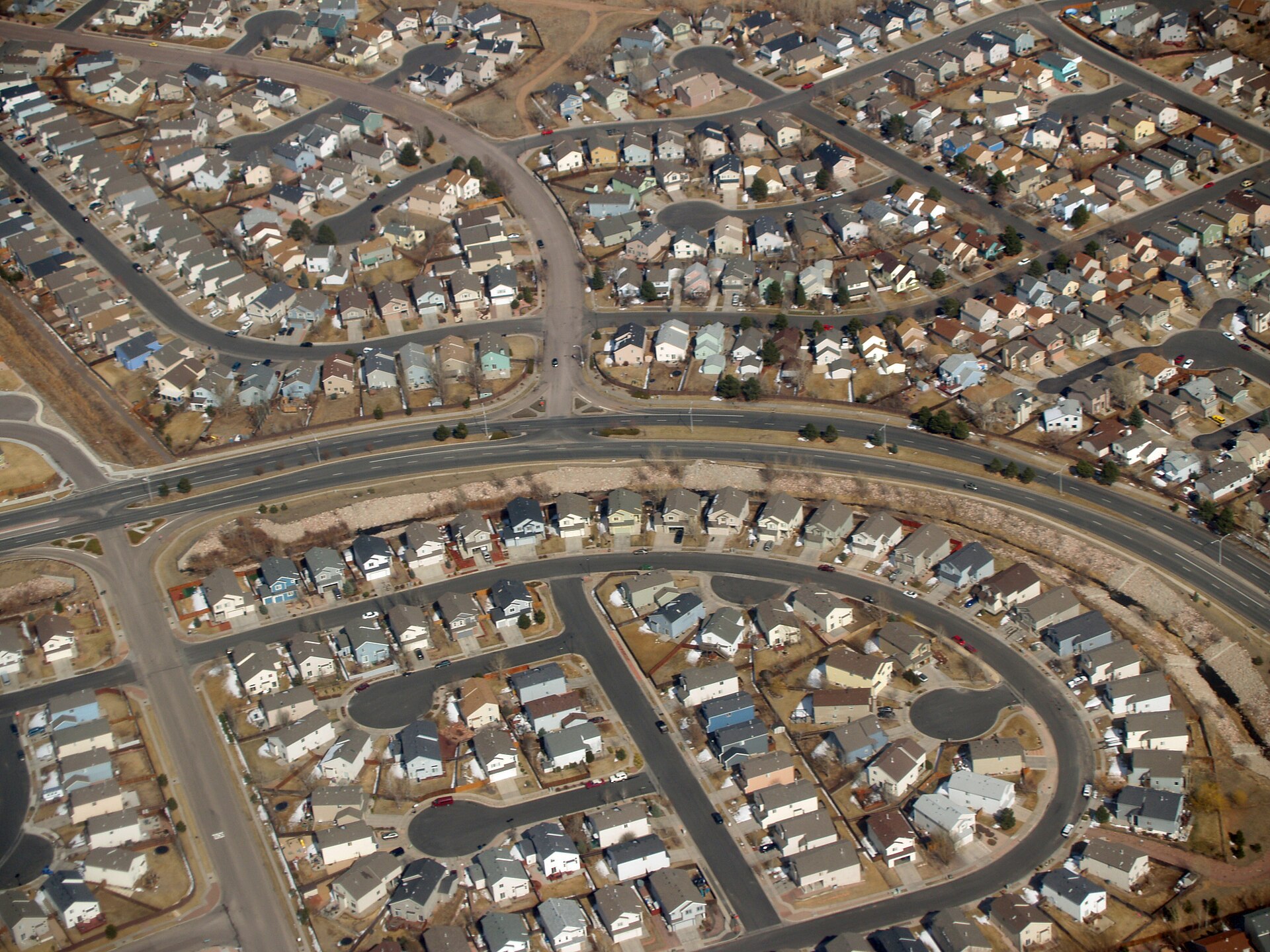 An aerial view of a suburban housing development with rows of single-family homes and streets.
